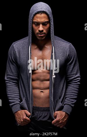 Mettre sa forme physique en marche. Photo en studio d'un jeune homme musclé portant un sweat à capuche isolé sur le noir. Banque D'Images