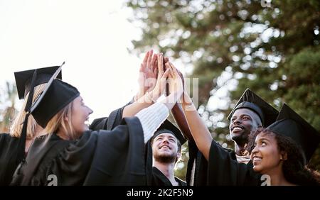 Poursuivre un avenir radieux. Photo d'un groupe d'étudiants qui se donnent un haut cinq le jour de la remise des diplômes. Banque D'Images