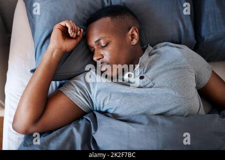 Dormir est le meilleur. Plan court d'un beau jeune homme qui dormait dans son lit pendant une journée de congé à la maison seule. Banque D'Images