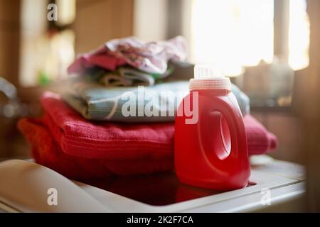 Nettoyage de votre linge. Prise d'une bouteille de détergent et d'une pile de linge sur un lave-linge. Banque D'Images