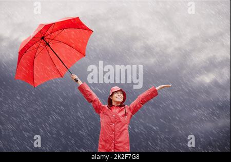 La pluie me rend heureux. Une belle jeune femme debout dehors avec son parapluie rouge. Banque D'Images