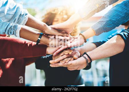 Un pour tous. Photo rognée d'un groupe méconnu d'amis d'université debout à l'extérieur avec leurs mains dans un caucus. Banque D'Images