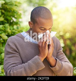 Renifle, éternue et wheezes. Photo d'un jeune homme soufflant son nez à l'extérieur. Banque D'Images