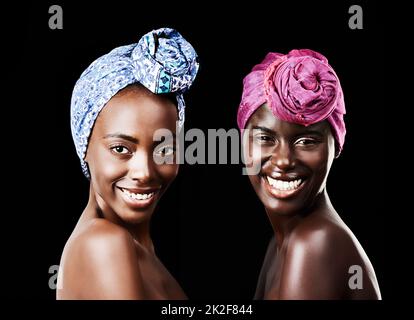 Des foulards superbes. Portrait studio de deux belles femmes portant un foulard sur fond noir. Banque D'Images