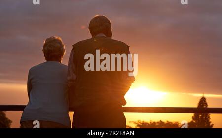 Ils aiment toujours le romantisme. Photo courte d'un couple âgé partageant un moment romantique au coucher du soleil. Banque D'Images