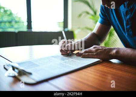 C'est mieux de tout obtenir sur le papier. Gros plan d'un homme méconnaissable remplissant des documents administratifs à une table. Banque D'Images