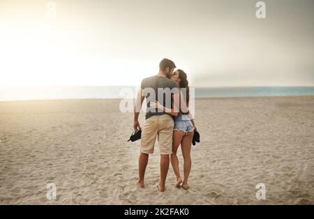 Promenades romantiques en bord de mer au coucher du soleil. Photo d'un jeune couple passant une journée romantique à la plage. Banque D'Images