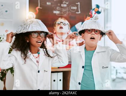 Étaient bien connus pour nos idées brillantes. Photo de deux adorables jeunes élèves qui font une expérience sur l'électricité et la lumière en classe scientifique à l'école. Banque D'Images