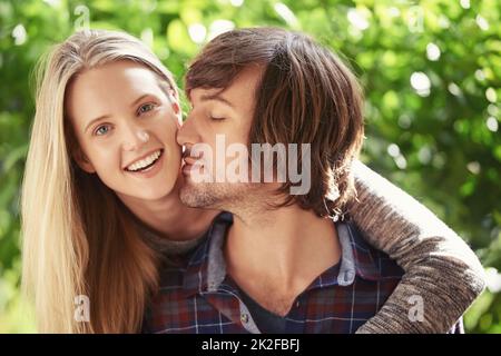 Jeune et plein de passion. Portrait d'un jeune couple souriant qui s'embrasse dans le parc. Banque D'Images