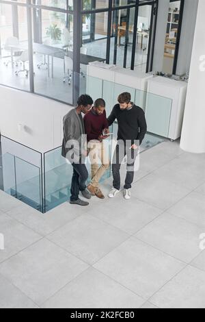 Travailler ensemble sur un nouveau projet. Photo d'un groupe d'hommes d'affaires ayant une discussion sur une tablette numérique. Banque D'Images