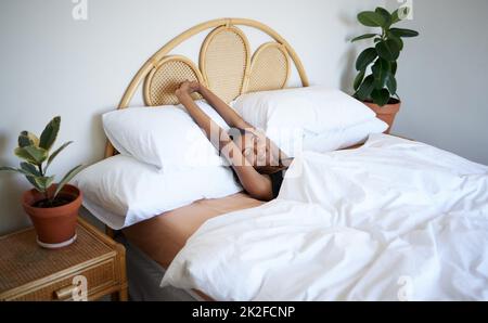 Je suis prêt pour une nouvelle journée. Prise de vue d'une jeune femme qui s'étire les bras après s'être réveillée. Banque D'Images