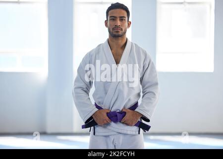 Mi presque au sommet. Portrait court d'un beau jeune homme d'artiste martial debout avec ses mains sur sa ceinture dans la salle de sport. Banque D'Images