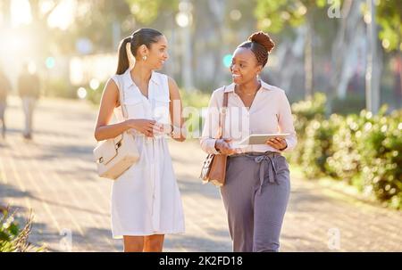 Avez-vous eu un Bonne journée. Photo de deux jeunes femmes d'affaires qui marchent ensemble dans la ville pendant leur trajet de l'après-midi depuis le bureau. Banque D'Images