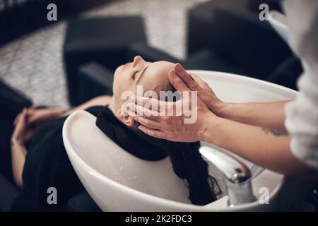 De beaux cheveux commencent avec un shampooing vraiment bon. Photo d'une belle jeune femme qui se lavait ses cheveux au salon. Banque D'Images