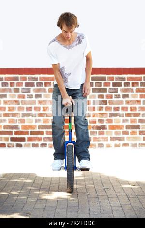 HES a des compétences. Photo en pleine longueur d'un jeune homme qui se balance sur un monocycle. Banque D'Images