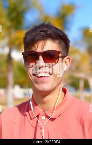 Été, soleil et quelques morceaux. Un jeune homme heureux qui écoute de la musique au soleil. Banque D'Images