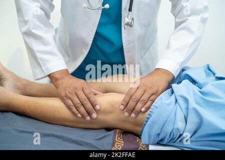 Médecin asiatique physiothérapeute examinant, massant et traitement genou et jambe d'un patient senior dans la clinique orthopédique infirmière hôpital. Banque D'Images