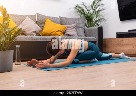 Belle jeune fille va pour le sport sur un tapis de gymnastique à la maison. Banque D'Images