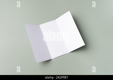 Maquette blanche d'une brochure tripliante blanche sur fond vert pâle. Maquette de carte. Banque D'Images