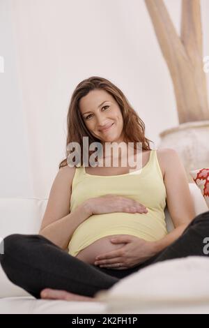 La grossesse est une belle chose. Portraitof une jeune femme enceinte dans son salon. Banque D'Images