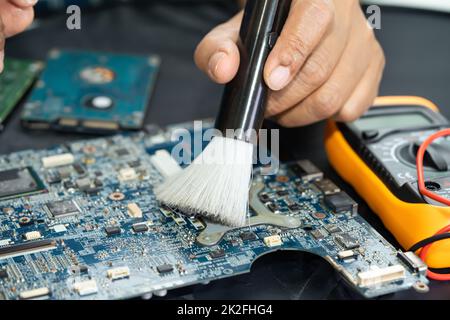 Le technicien utilise une brosse et une boule de soufflerie d'air pour nettoyer la poussière de l'ordinateur de la carte de circuit imprimé. Réparer la technologie de mise à niveau et de maintenance. Banque D'Images