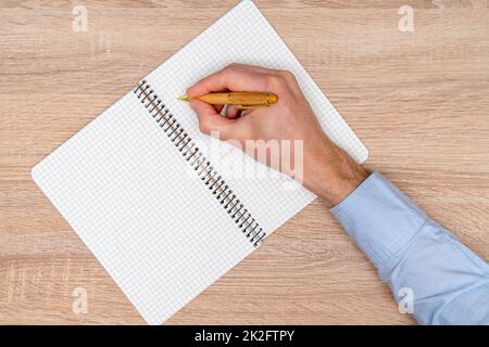 Vue de dessus hommes écriture à la main avec un stylo dans un cahier en spirale Banque D'Images
