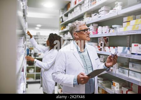 Faire le plein. Photo de deux pharmaciens spécialisés qui se promo et qui font du stock à l'intérieur d'une pharmacie. Banque D'Images