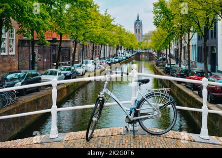 Vélo sur le pont et le canal avec des voitures garées le long et Ancienne église Oude Kerk dans la rue Delft Banque D'Images