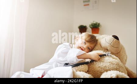 Le cœur de mes patients déborde d'amour. Photo d'une adorable petite fille vêtue comme médecin et traitant son ours en peluche comme une patiente. Banque D'Images