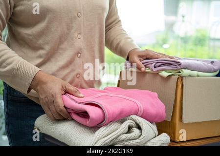 Tenir la boîte de dons de vêtements avec des vêtements usagés et une poupée à la maison pour aider les pauvres dans le monde. Banque D'Images