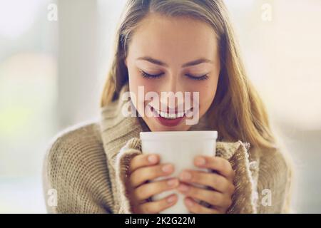 Réveillez-vous et sentez le café. Portrait d'une jeune femme prenant une boisson chaude à la maison. Banque D'Images