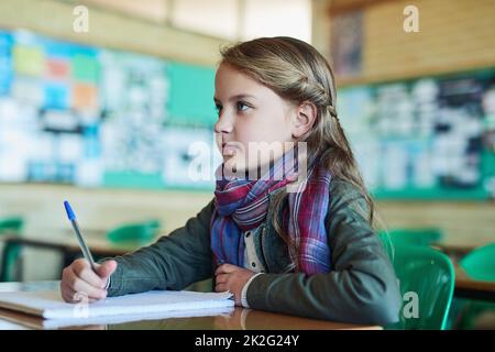 Écouter attentivement en classe. Photo d'une fille de l'école primaire travaillant en classe. Banque D'Images