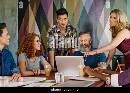 Rassembler leurs meilleures idées. Photo d'un groupe de concepteurs travaillant ensemble sur un ordinateur portable dans un bureau. Banque D'Images