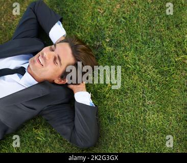 Juste prendre un reniflard. Un jeune homme d'affaires couché sur l'herbe verte. Banque D'Images