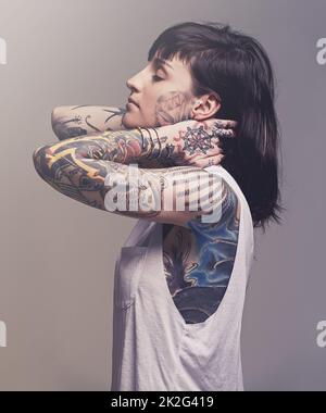 Embellissement. Un petit portrait de studio d'une jeune femme tatouée. Banque D'Images