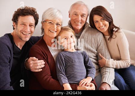 Nous sommes un autre bonheur. Portrait court d'une famille de plusieurs générations heureuse assise ensemble sur un canapé. Banque D'Images