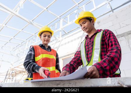 L'architecte et le client discutent de l'aide à la création d'un plan avec le plan du bâtiment sur le chantier de construction Banque D'Images