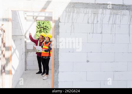 Architecte et client discutant du plan avec le plan du bâtiment sur le chantier de construction Banque D'Images