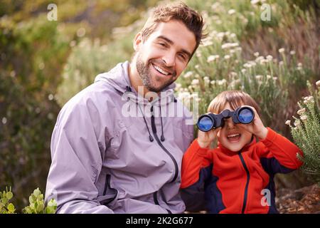 Sur la promenade pour quelques animaux sauvages. Photo d'un petit garçon regardant à travers des jumelles pendant une randonnée avec son père. Banque D'Images