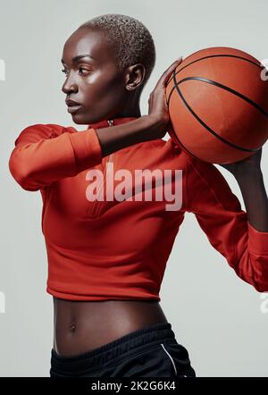 La grandeur est le but. Photo en studio d'une jeune femme attrayante jouant au basket-ball sur fond gris. Banque D'Images