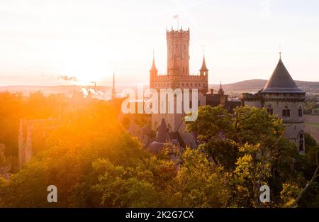 Pattensen, Germany. 23rd Sep, 2022. The rising sun bathes the forests and Marienburg Castle in the Hanover region in a warm light in the early morning. September 23 marks the beginning of autumn. Credit: Julian Stratenschulte/dpa/Alamy Live News Stock Photo