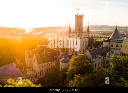 Pattensen, Germany. 23rd Sep, 2022. The rising sun bathes the forests and Marienburg Castle in the Hanover region in a warm light in the early morning. September 23 marks the beginning of autumn. Credit: Julian Stratenschulte/dpa/Alamy Live News Stock Photo