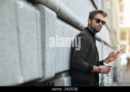 HES, une ville qui s'élance. Photo rognée d'un beau jeune homme envoyant un texte tout en voyageant dans la ville. Banque D'Images