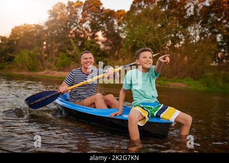 Profitez d'une promenade lente sur la rivière. Photo d'un père et d'un fils rasant un bateau ensemble sur un lac. Banque D'Images