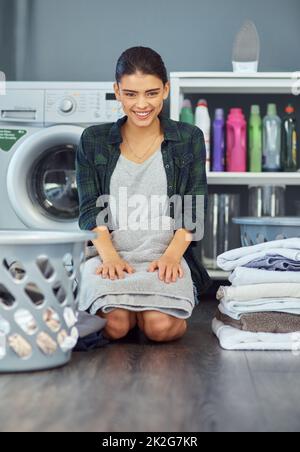 Je plie toujours mon linge immédiatement. Portrait en longueur d'une jeune femme attirante pliant une serviette tout en faisant la lessive à la maison. Banque D'Images