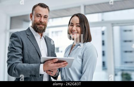 Réunir différentes expertises et perspectives. Portrait de deux hommes d'affaires utilisant une tablette numérique ensemble dans un bureau. Banque D'Images