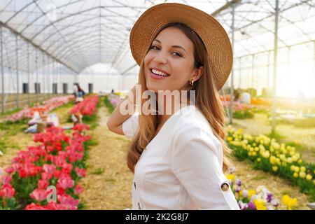 Portrait de la femme souriante tourne et regarde l'appareil photo marcher entre des tulipes Banque D'Images