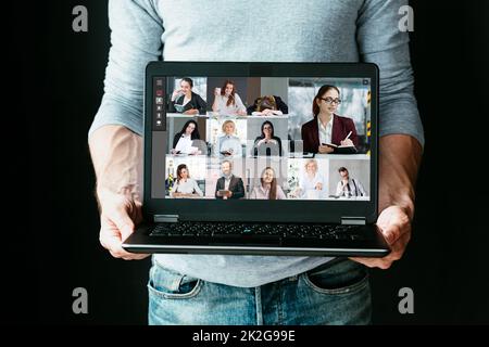 Group video chat. Business coaching. Distance education. Man holding laptop with people watching online webinar on screen in virtual class isolated on Stock Photo