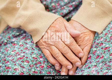 Asian elder senior woman patient sitting on bed in hospital, closeup at her hand. Banque D'Images