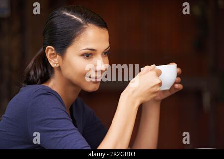 Letting the warmth sink in. A young woman drinking a cup of coffee outside. Stock Photo